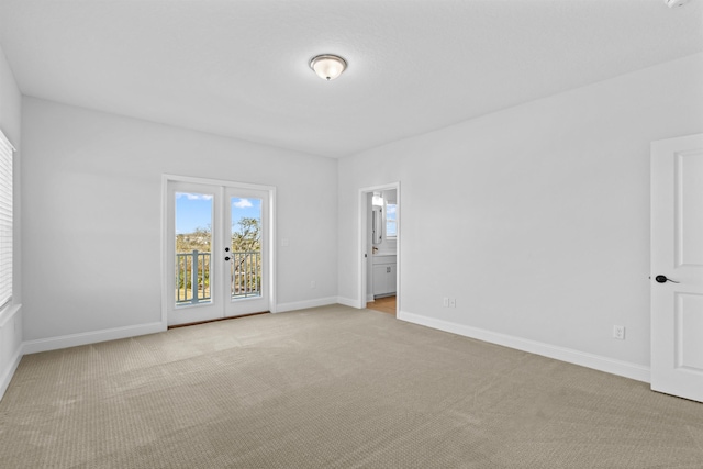 empty room with baseboards, french doors, and light colored carpet