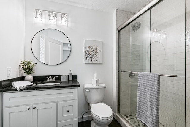 bathroom with a textured ceiling, vanity, toilet, and an enclosed shower