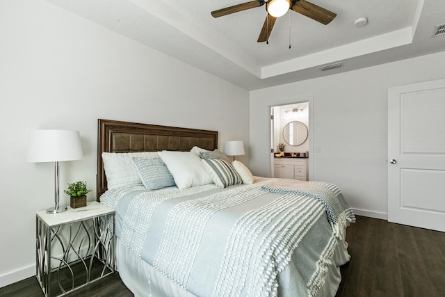 bedroom with a tray ceiling, connected bathroom, ceiling fan, and dark hardwood / wood-style floors