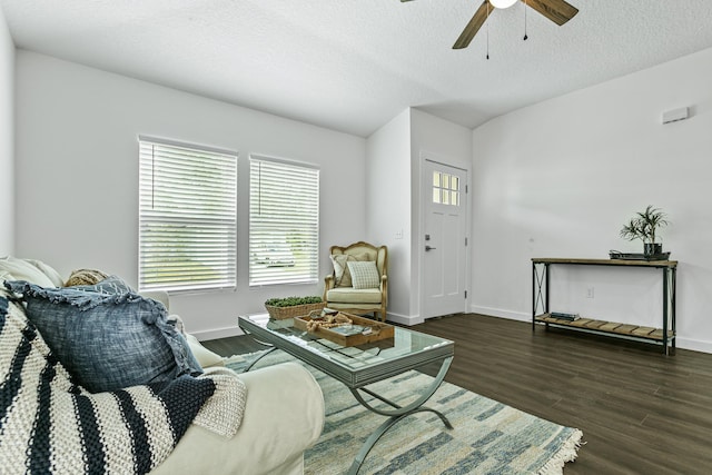 living room featuring dark hardwood / wood-style floors, ceiling fan, and a textured ceiling