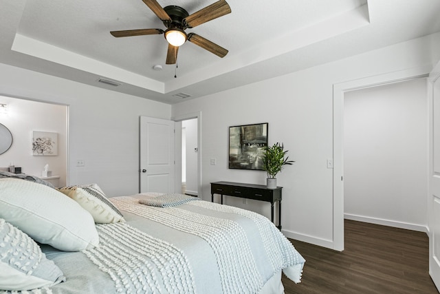 bedroom with dark hardwood / wood-style floors, a raised ceiling, and ceiling fan