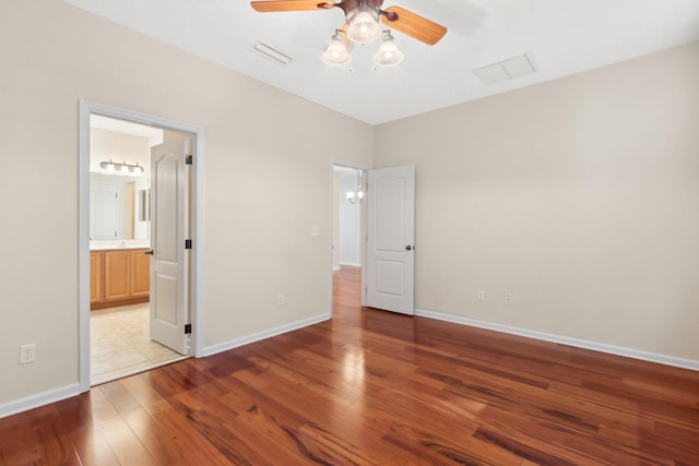 unfurnished bedroom featuring ensuite bath, ceiling fan, and light wood-type flooring