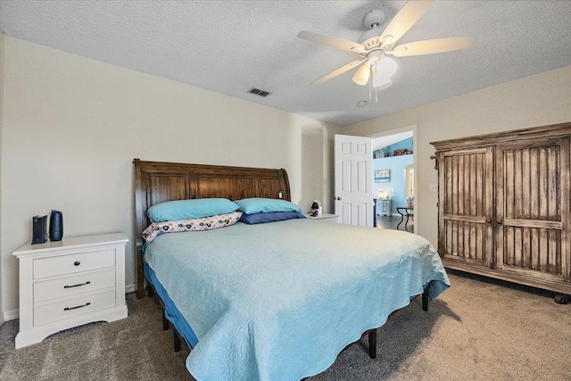 bedroom with ceiling fan, a textured ceiling, and dark carpet