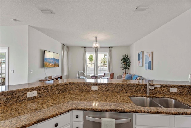 28 S Comares Ave, Saint Augustine, FL 32080 - kitchen with stainless steel dishwasher, a sink, white cabinets, dark stone countertops, and a textured ceiling