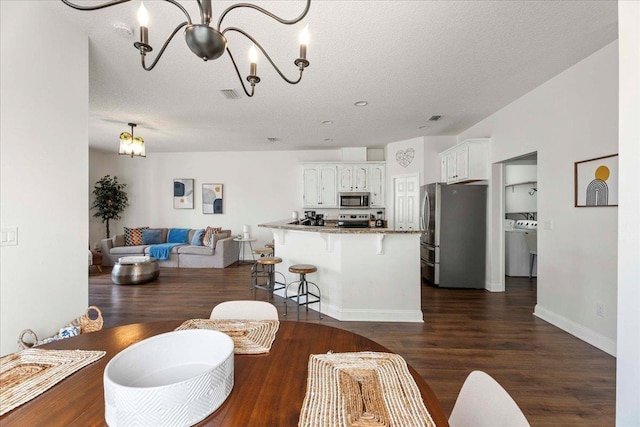 28 S Comares Ave, Saint Augustine, FL 32080 - living area featuring a chandelier, dark wood-type flooring, a textured ceiling, washer and dryer, and baseboards
