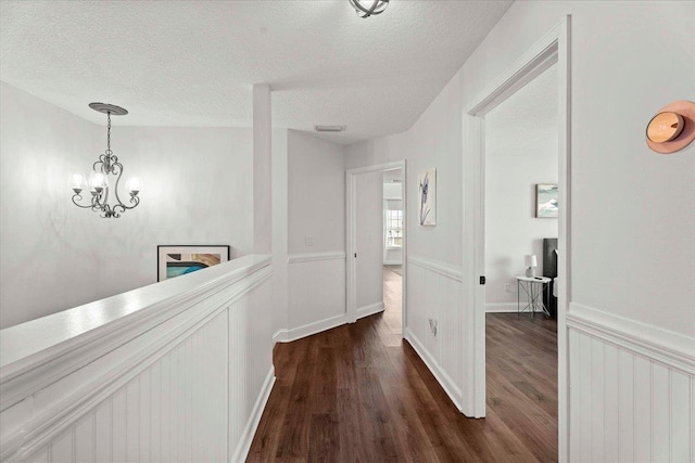 28 S Comares Ave, Saint Augustine, FL 32080 - corridor with dark wood-type flooring, a textured ceiling, a chandelier, and a wainscoted wall