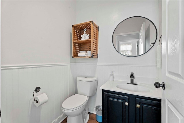 28 S Comares Ave, Saint Augustine, FL 32080 - half bath featuring vanity, toilet, a wainscoted wall, and wood finished floors