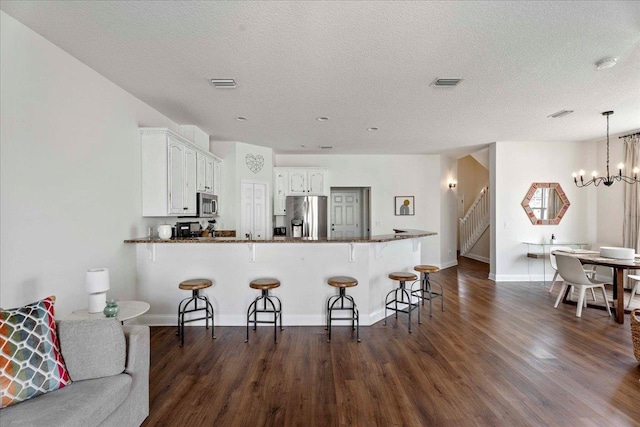 28 S Comares Ave, Saint Augustine, FL 32080 - kitchen with stainless steel appliances, white cabinets, dark wood-type flooring, a breakfast bar, and a peninsula