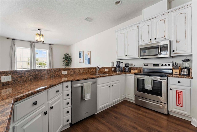 28 S Comares Ave, Saint Augustine, FL 32080 - kitchen featuring stainless steel appliances, a sink, white cabinets, dark wood-style floors, and a textured ceiling