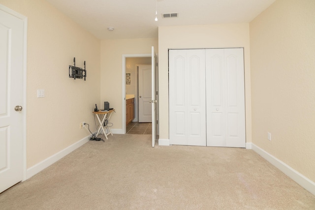 unfurnished bedroom with light carpet, connected bathroom, and a closet