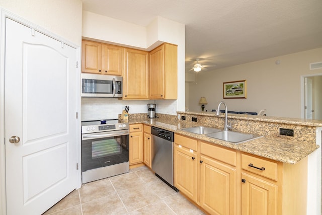 kitchen featuring sink, light tile patterned floors, light stone counters, kitchen peninsula, and stainless steel appliances