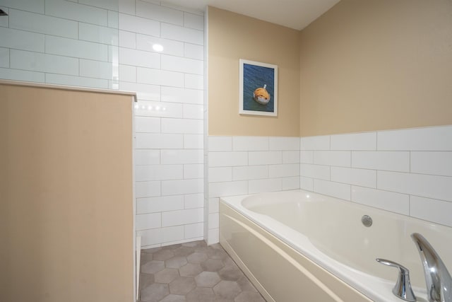 bathroom with tile patterned floors, a bathtub, and tile walls