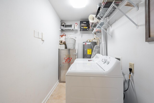 washroom with electric water heater, washer and clothes dryer, and light tile patterned flooring