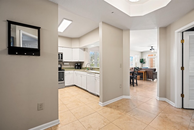 kitchen with stainless steel appliances, ceiling fan, sink, light tile patterned floors, and white cabinetry