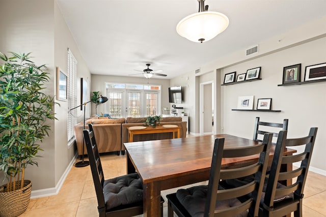 tiled dining room featuring ceiling fan and french doors