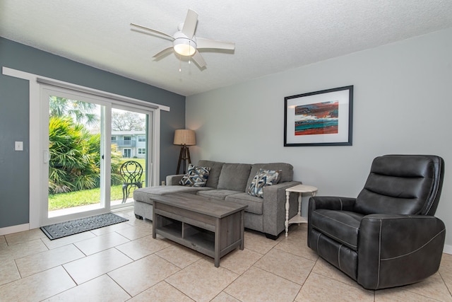 living room featuring ceiling fan, light tile patterned floors, and a textured ceiling