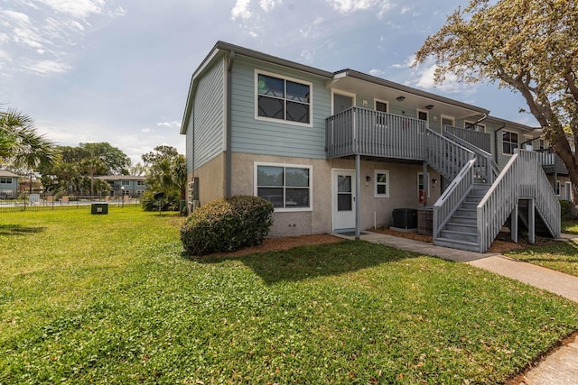 rear view of house featuring central AC unit and a yard