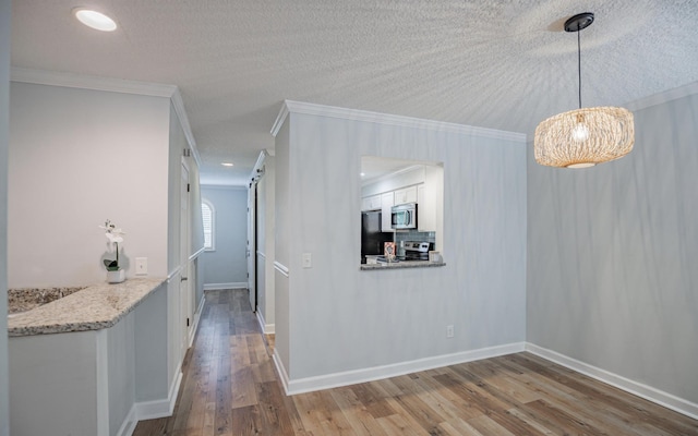 interior space featuring light hardwood / wood-style floors, ornamental molding, and a textured ceiling