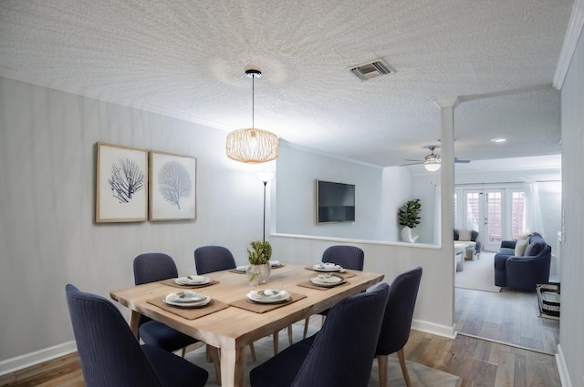 dining room with ceiling fan with notable chandelier, a textured ceiling, hardwood / wood-style flooring, and ornamental molding