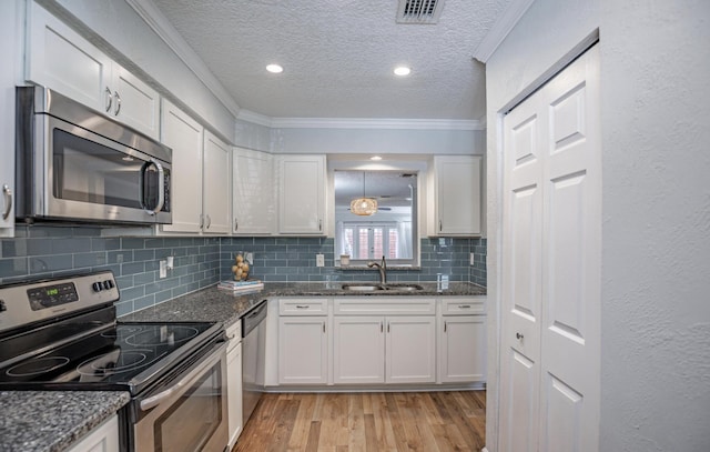 kitchen featuring appliances with stainless steel finishes, light wood-type flooring, crown molding, sink, and white cabinets