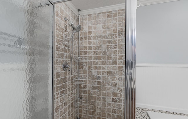 bathroom with crown molding, a shower with shower door, and a textured ceiling