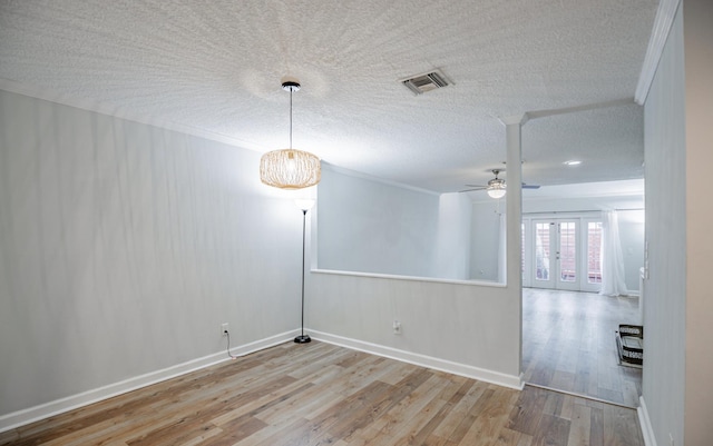 empty room with ceiling fan, french doors, crown molding, light hardwood / wood-style floors, and a textured ceiling