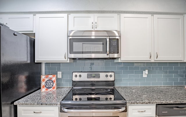 kitchen featuring white cabinets, appliances with stainless steel finishes, tasteful backsplash, and dark stone counters