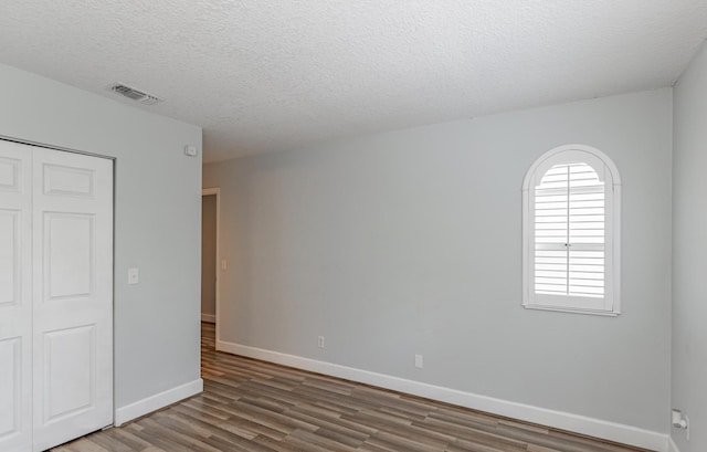 empty room with a textured ceiling and hardwood / wood-style flooring