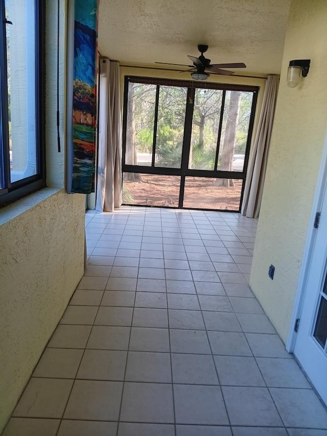 unfurnished sunroom featuring a ceiling fan