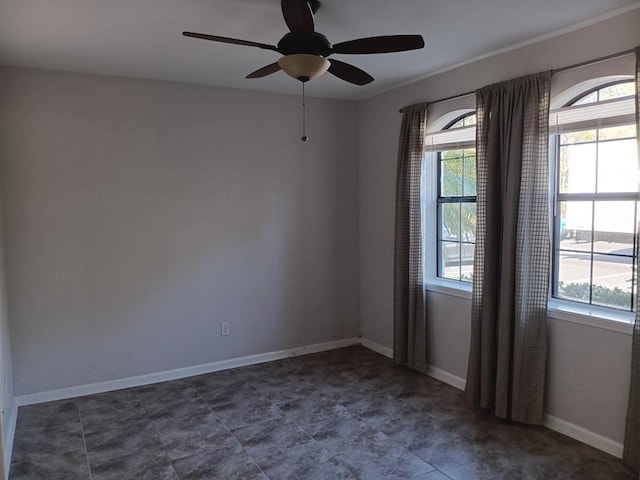 spare room with a ceiling fan and baseboards