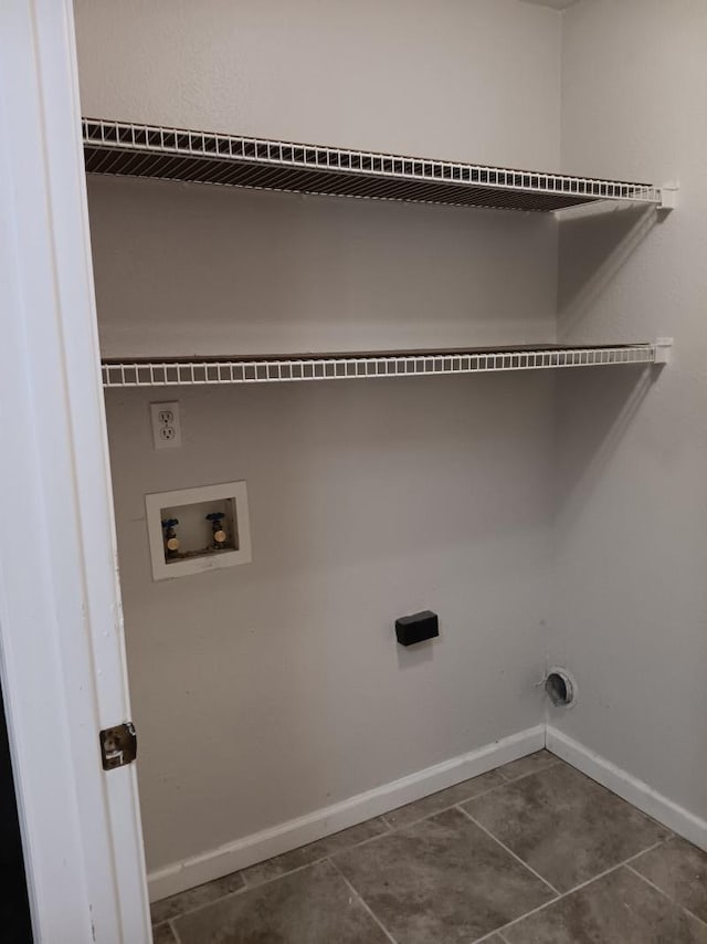 laundry area featuring baseboards, washer hookup, dark tile patterned floors, and laundry area