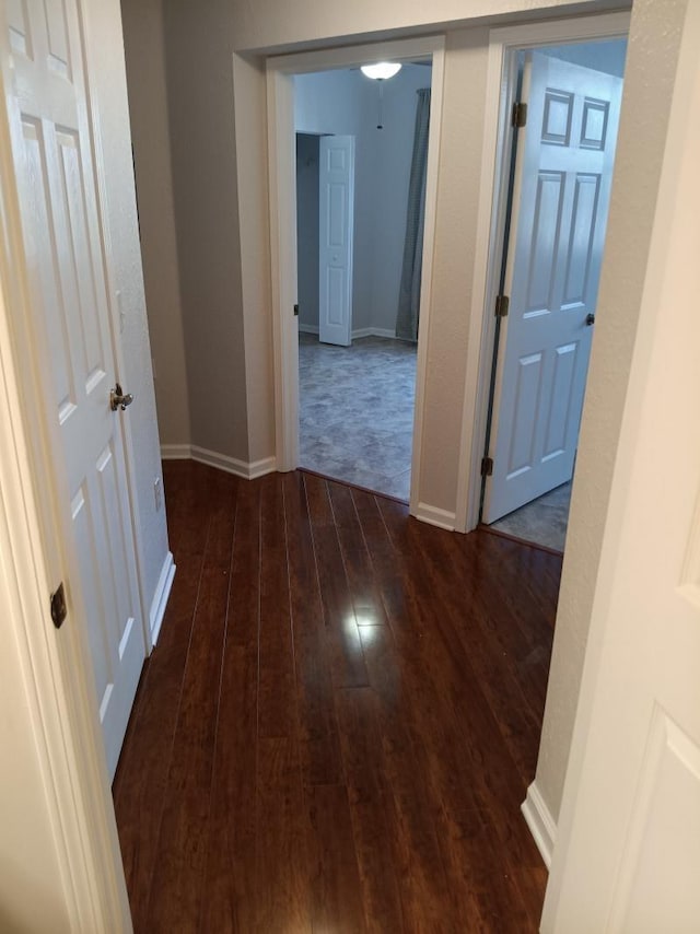 hallway with baseboards and dark wood finished floors