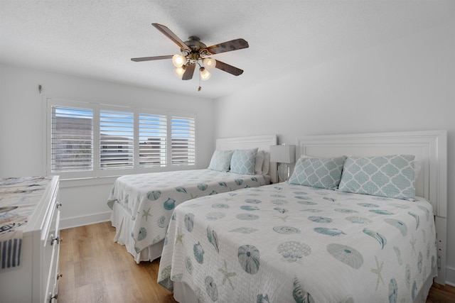 bedroom with a textured ceiling, light hardwood / wood-style flooring, and ceiling fan