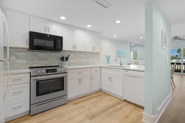 kitchen featuring white dishwasher, stainless steel electric stove, sink, light hardwood / wood-style floors, and white cabinetry