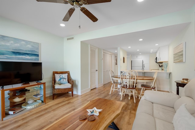 living room featuring ceiling fan and light hardwood / wood-style flooring