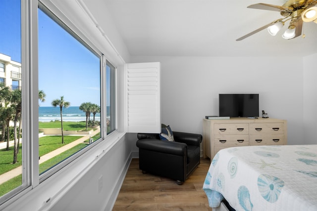 bedroom featuring ceiling fan, hardwood / wood-style floors, and a water view