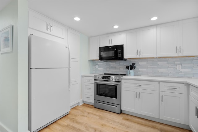 kitchen with stainless steel electric stove, white cabinets, and white fridge