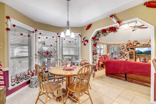 tiled dining space featuring ceiling fan with notable chandelier