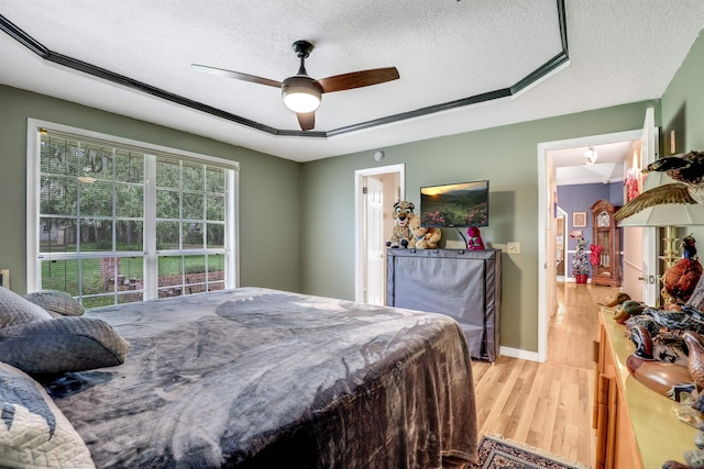 bedroom with a textured ceiling, light hardwood / wood-style floors, and ceiling fan