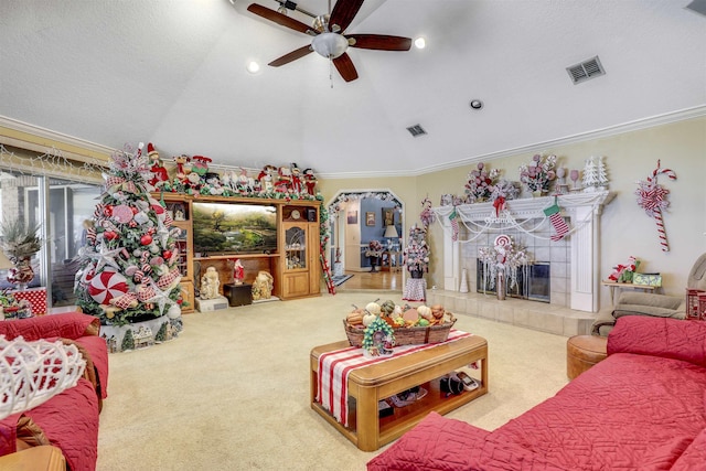 carpeted living room with a tile fireplace, ceiling fan, a textured ceiling, vaulted ceiling, and ornamental molding