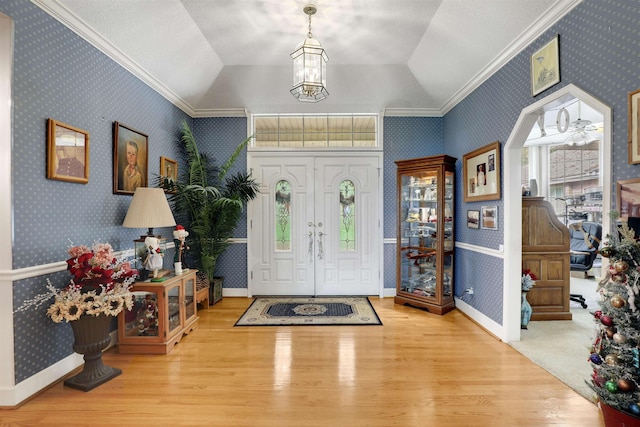 entryway with light hardwood / wood-style floors, vaulted ceiling, and ornamental molding