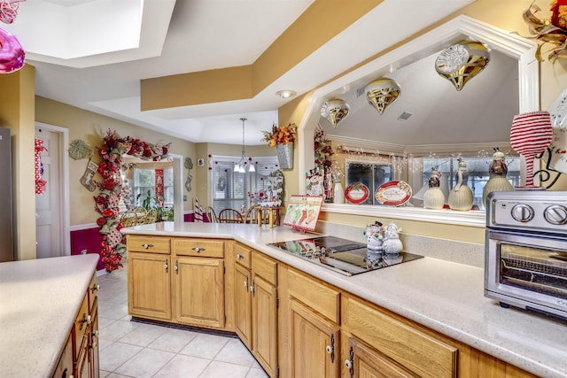 kitchen with a skylight, black electric cooktop, a raised ceiling, light tile patterned floors, and hanging light fixtures