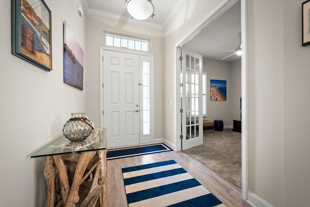 foyer entrance featuring crown molding, ceiling fan, light wood-type flooring, and a wealth of natural light