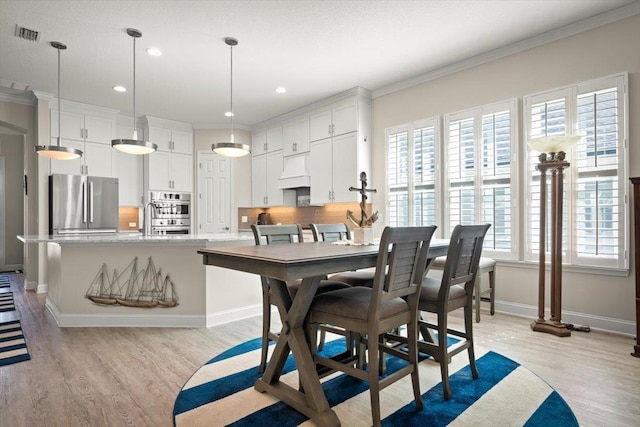 dining space featuring ornamental molding and light hardwood / wood-style floors