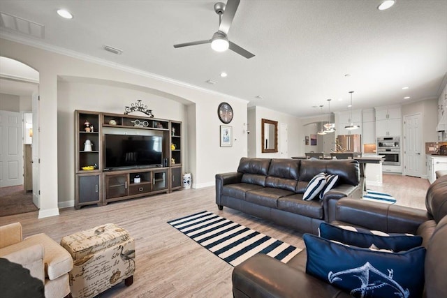 living room with ornamental molding, light hardwood / wood-style floors, and ceiling fan