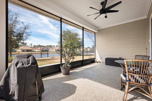 sunroom featuring ceiling fan and a water view