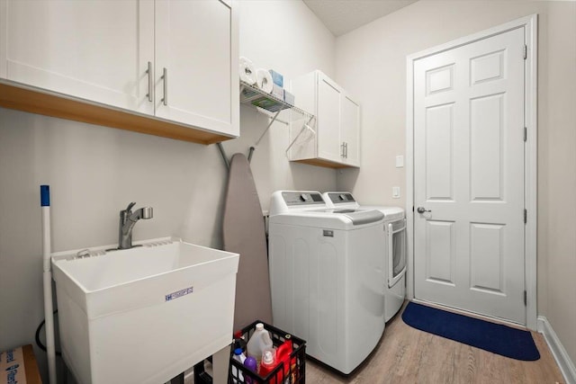 laundry area with cabinets, light hardwood / wood-style floors, sink, and washer and dryer