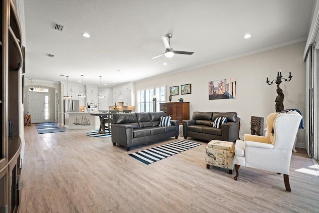 living room with crown molding, ceiling fan, and light hardwood / wood-style floors