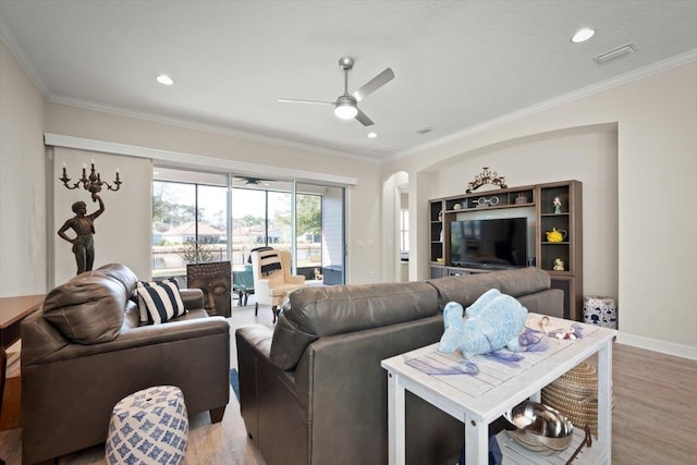 living room with ornamental molding, light hardwood / wood-style floors, and ceiling fan