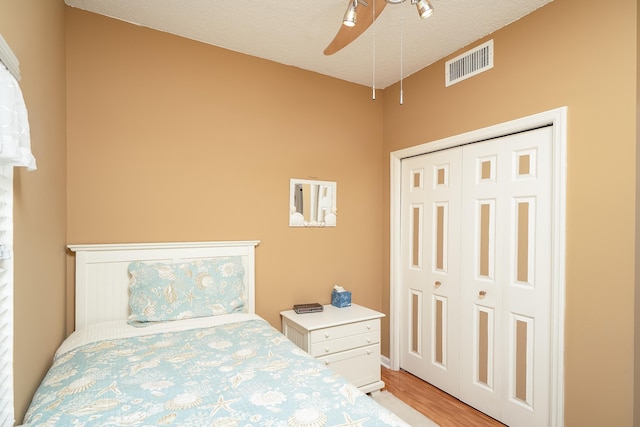 bedroom featuring a textured ceiling, light wood-type flooring, a closet, and ceiling fan